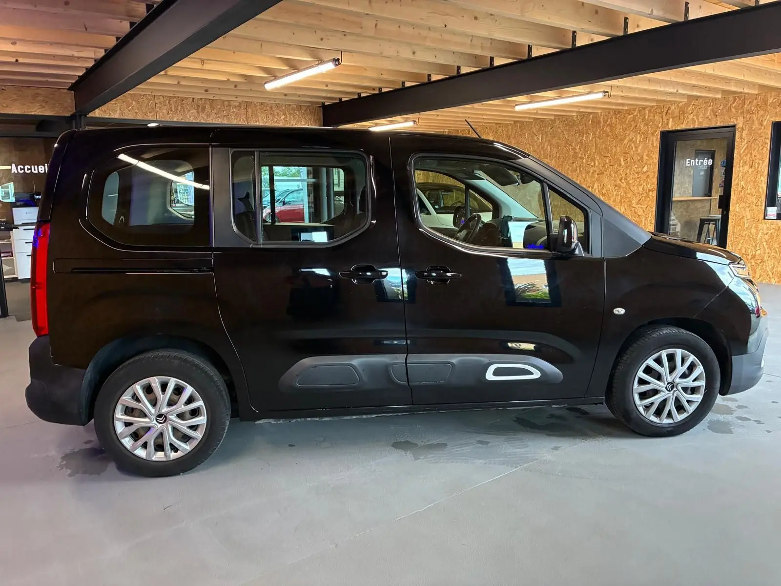 Profil côté gauche d'un Citroën Berlingo noir 2020 en intérieur, avec portes coulissantes et jantes alliage visibles.