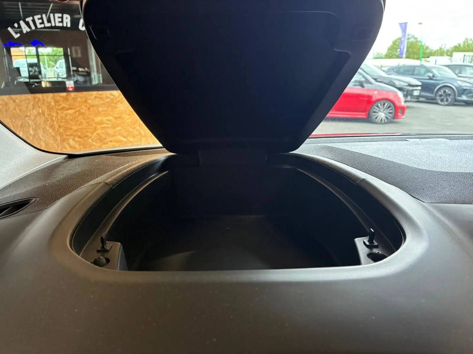 Vue rapprochée du coffre de rangement ouvert sur le tableau de bord du Citroën Berlingo noir, intérieur tissu noir visible.