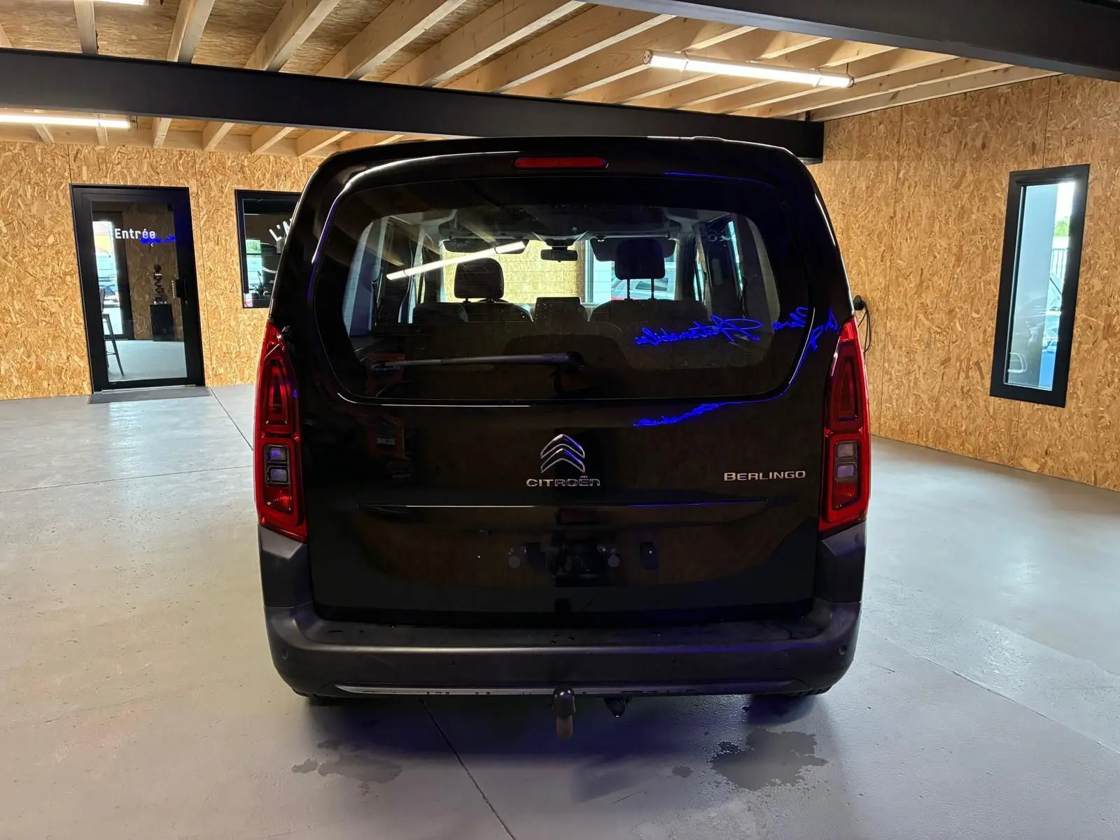 Vue arrière d'un Citroën Berlingo noir 2020 dans un garage avec attelage visible sous le pare-chocs.