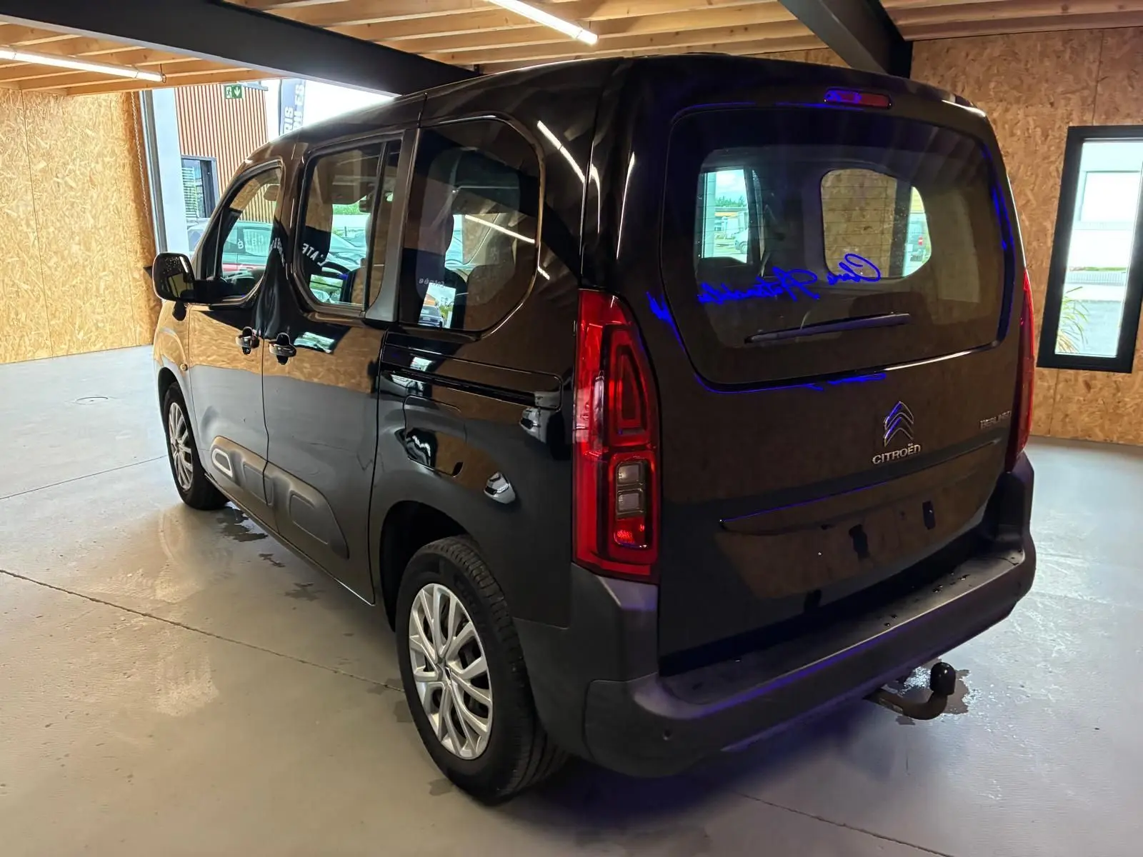 Vue 3/4 arrière droite d'un Citroën Berlingo noir 2020 avec hayon, feux arrière verticaux et attelage visible.