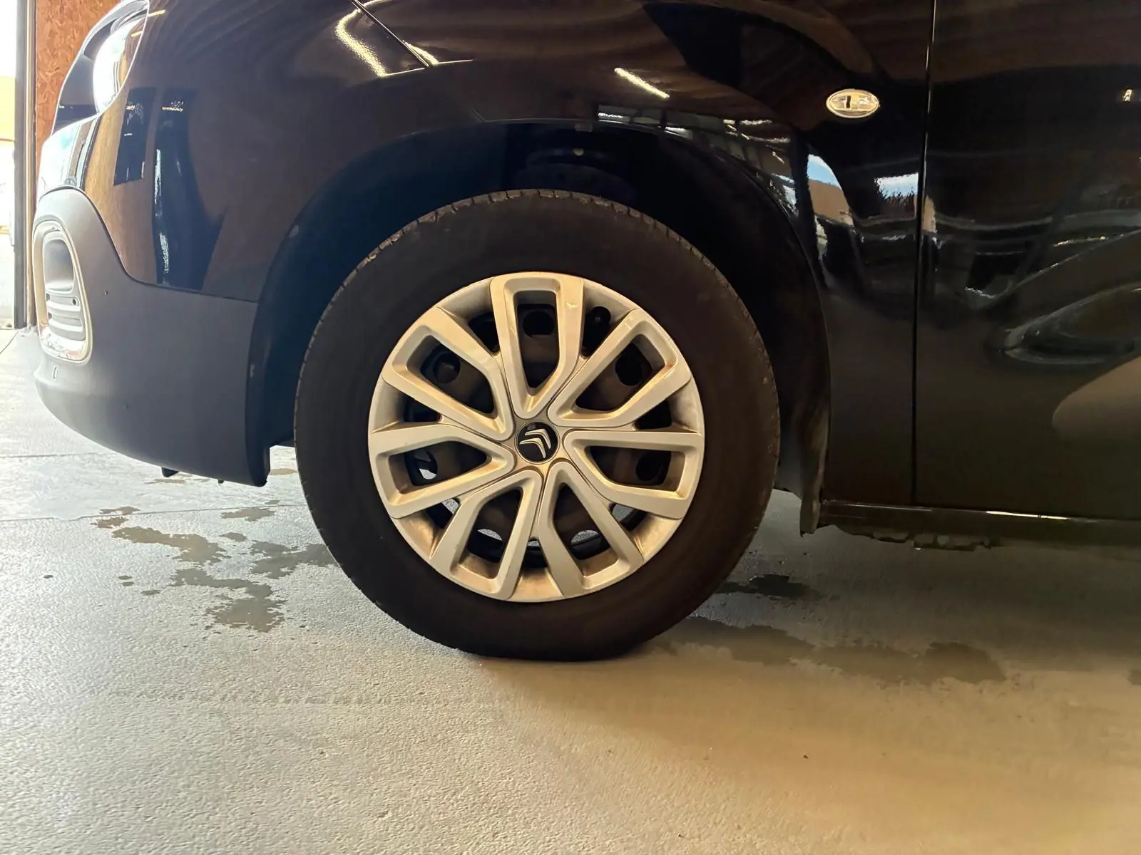 Gros plan sur la roue avant gauche d’un Citroën Berlingo noir 2020 avec jante alliage distinctive et badge 1.5 BlueHDi.