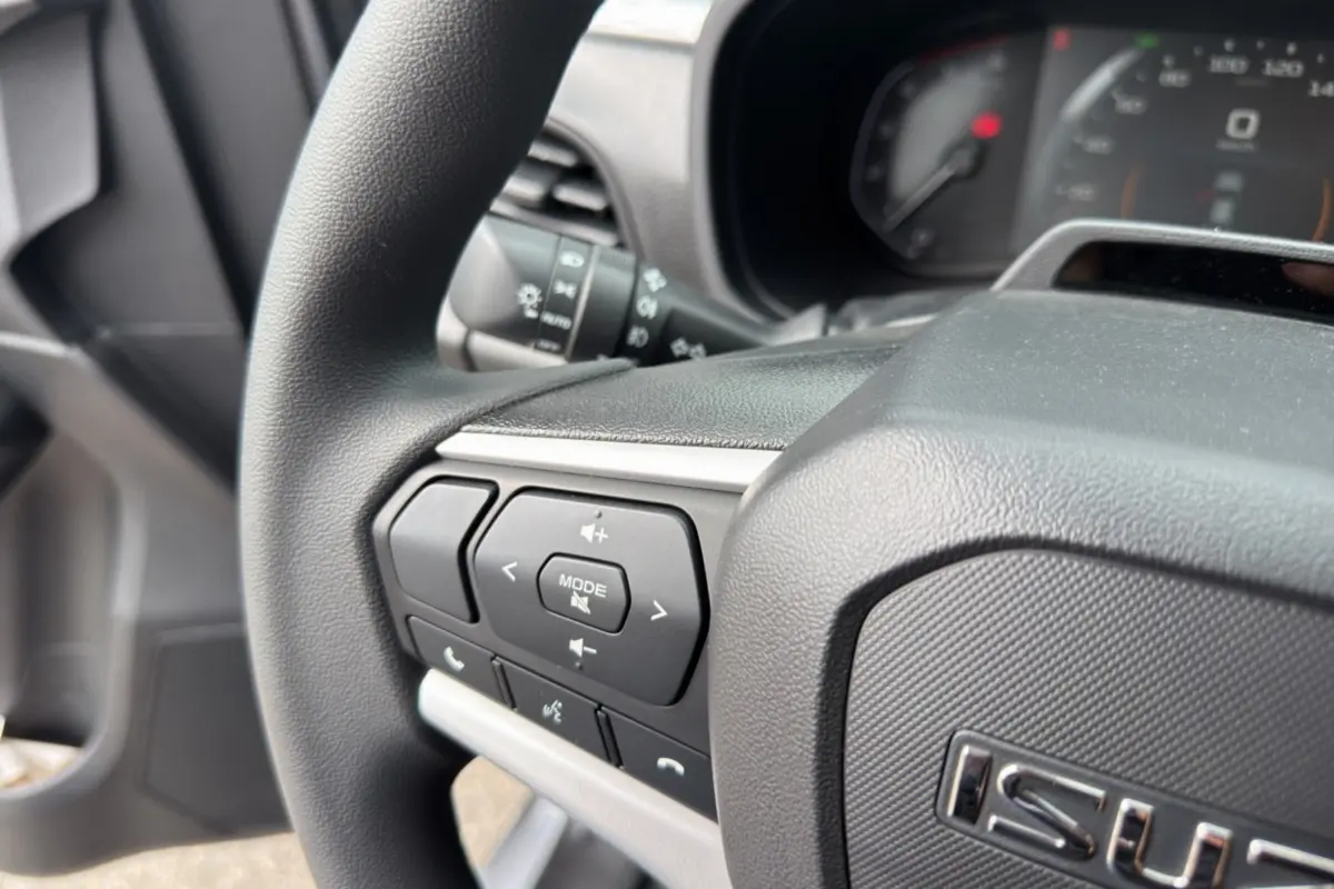 Gros plan sur le volant multifonctions du pick-up Isuzu D-MAX 2.2 TD 164 Space Evolution, intérieur noir.