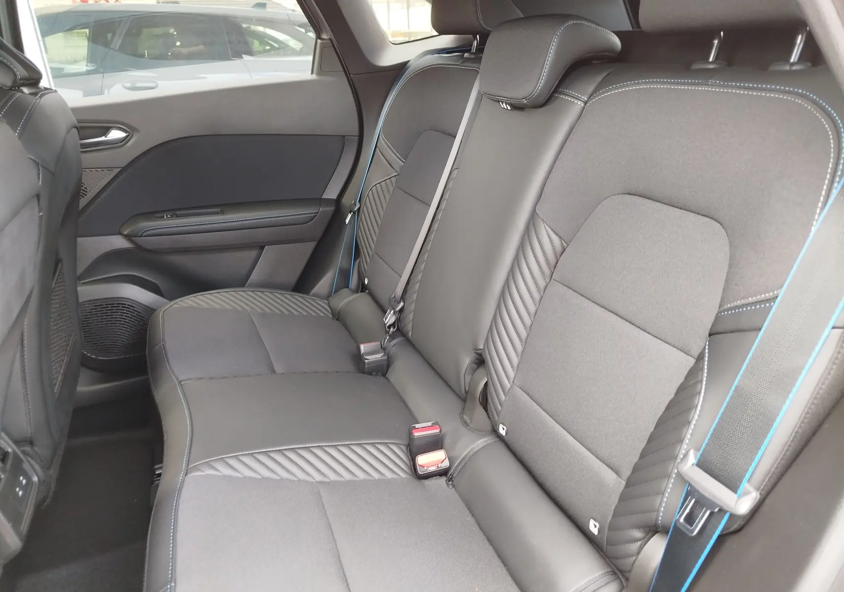 Vue latérale intérieure de la banquette arrière en tissu noir avec surpiqûres bleues du Renault Symbioz 2026.