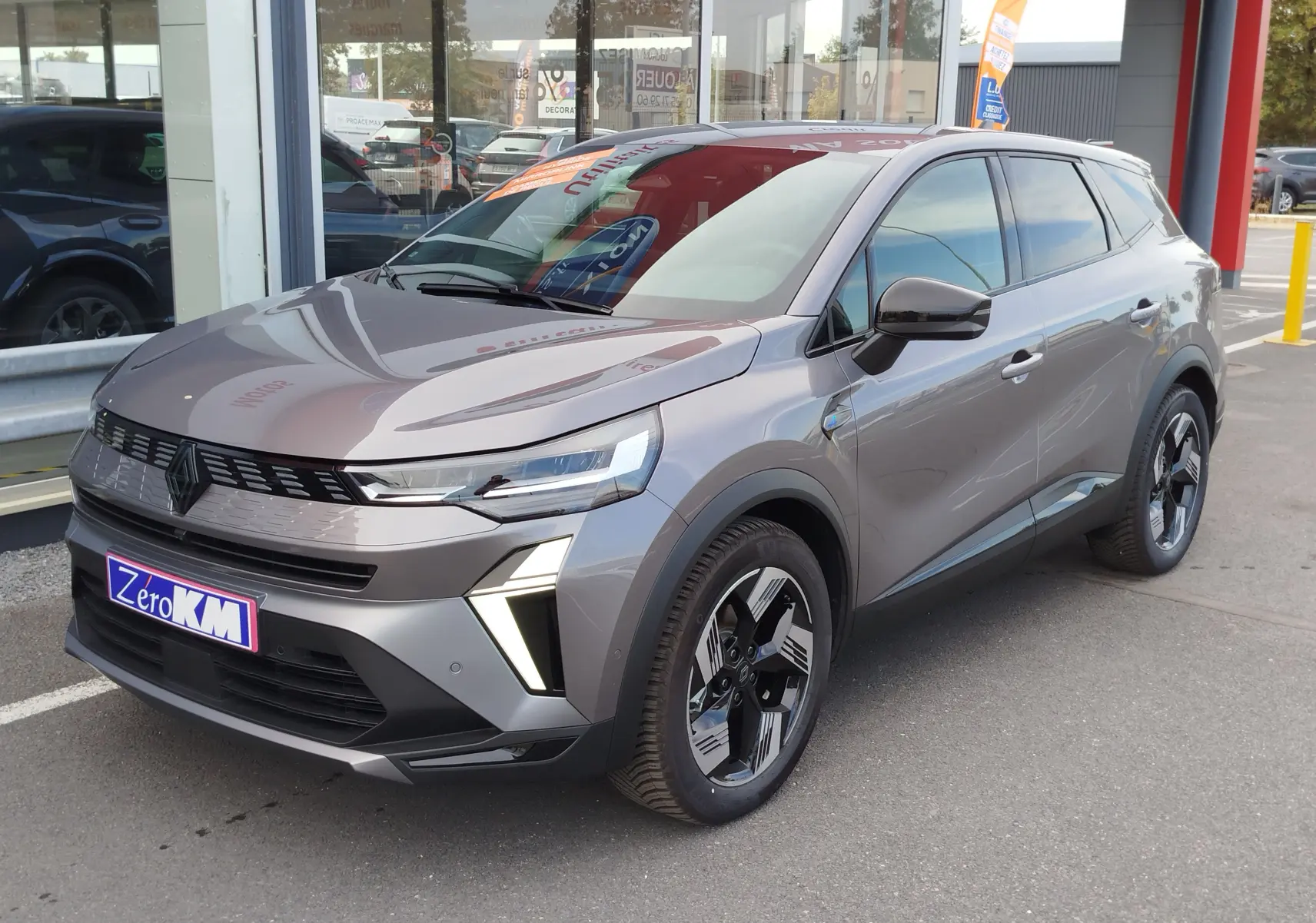 Renault Symbioz gris cassiopée métal en 3/4 avant droit, avec calandre moderne et feux LED verticaux distinctifs.