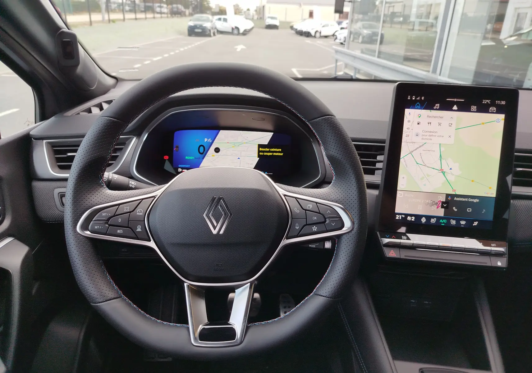 Vue intérieure centrée sur le volant noir perforé et l'écran tactile vertical du Renault Symbioz gris Cassiopée.