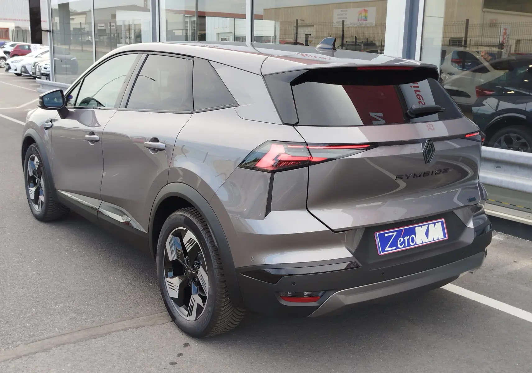 Vue 3/4 arrière droite du Renault Symbioz gris cassiopée métallisé avec feux arrière LED et jantes noires distinctives.