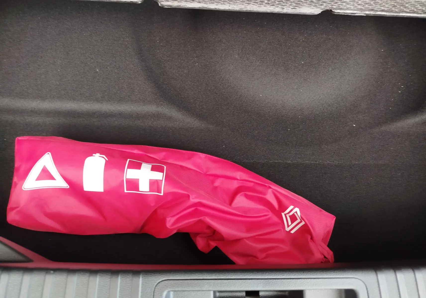 Rangement intérieur du coffre d'une Renault SYMBIOZ gris cassiopée, avec une trousse de secours rouge visible.