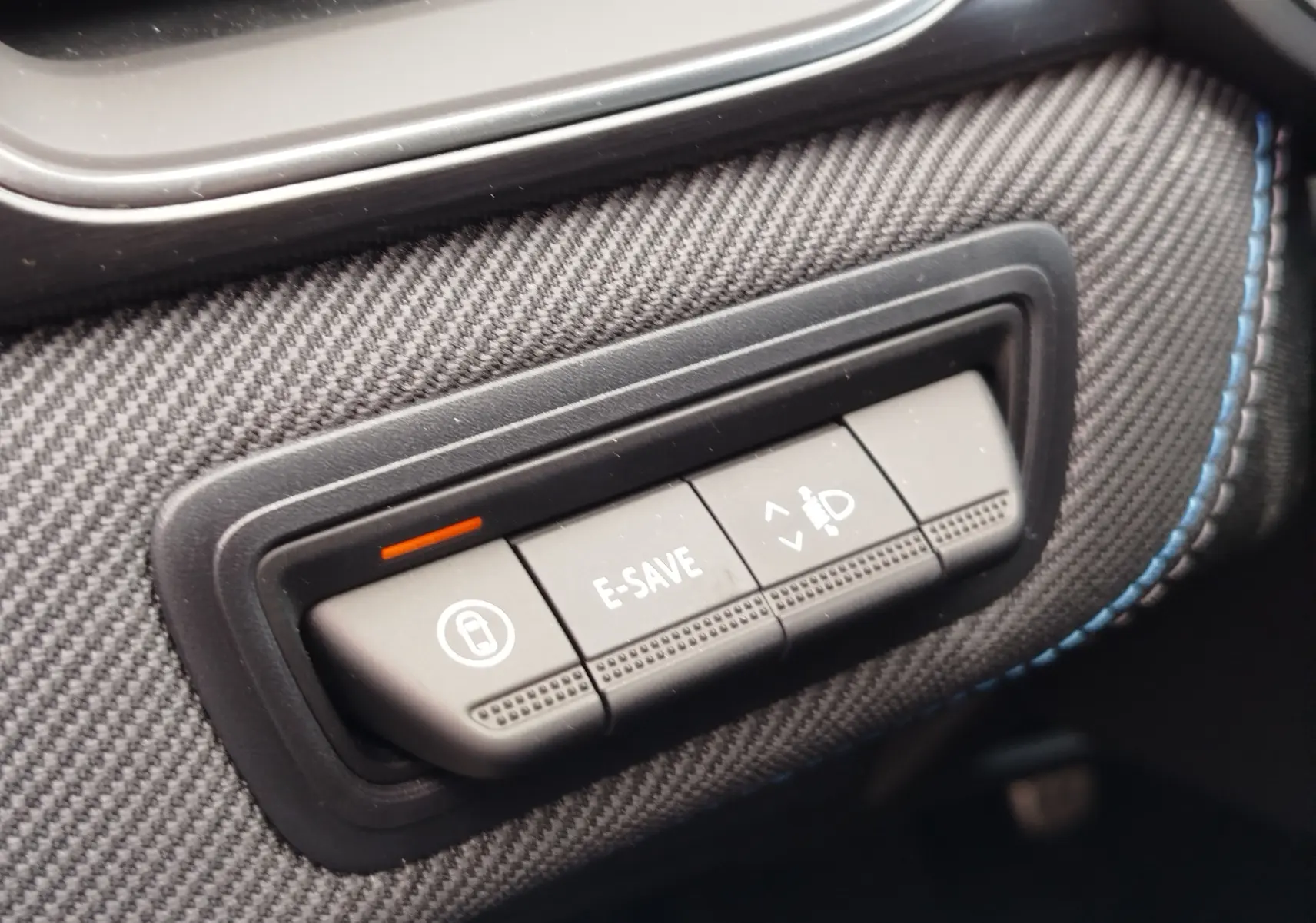 Gros plan sur les boutons de commande E-SAVE et réglage des phares, habillage carbone avec surpiqûres bleues, intérieur Renault Symbioz.