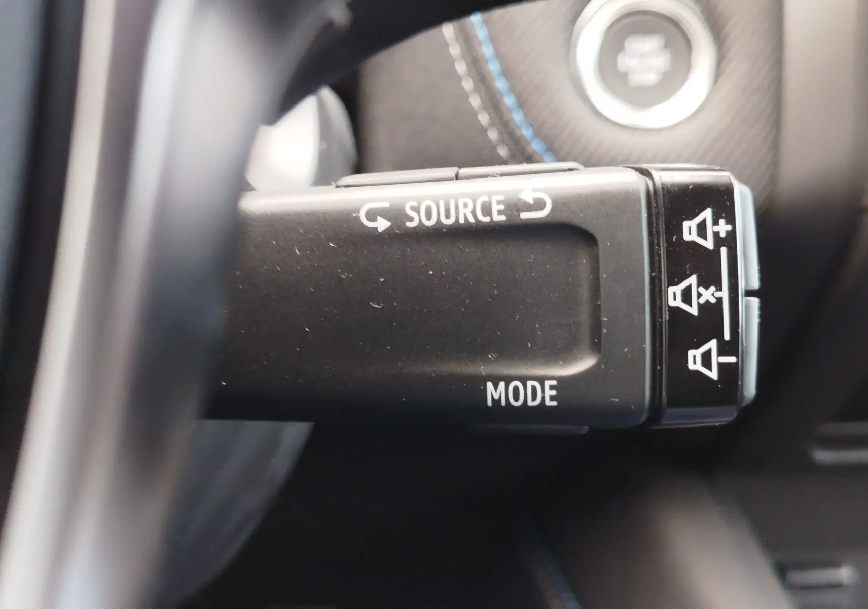Gros plan sur la commande au volant noire du Renault Symbioz 2026, avec boutons source et mode visibles.