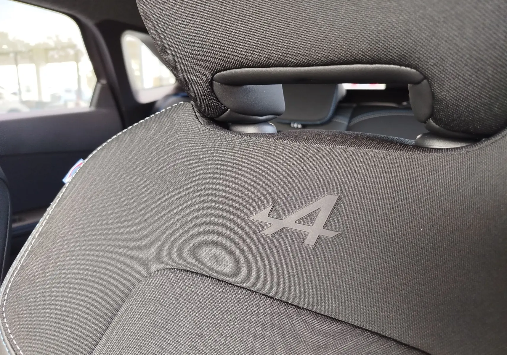 Gros plan sur le dossier de siège avant noir avec logo Alpine embossé, intérieur du Renault Symbioz 2026.