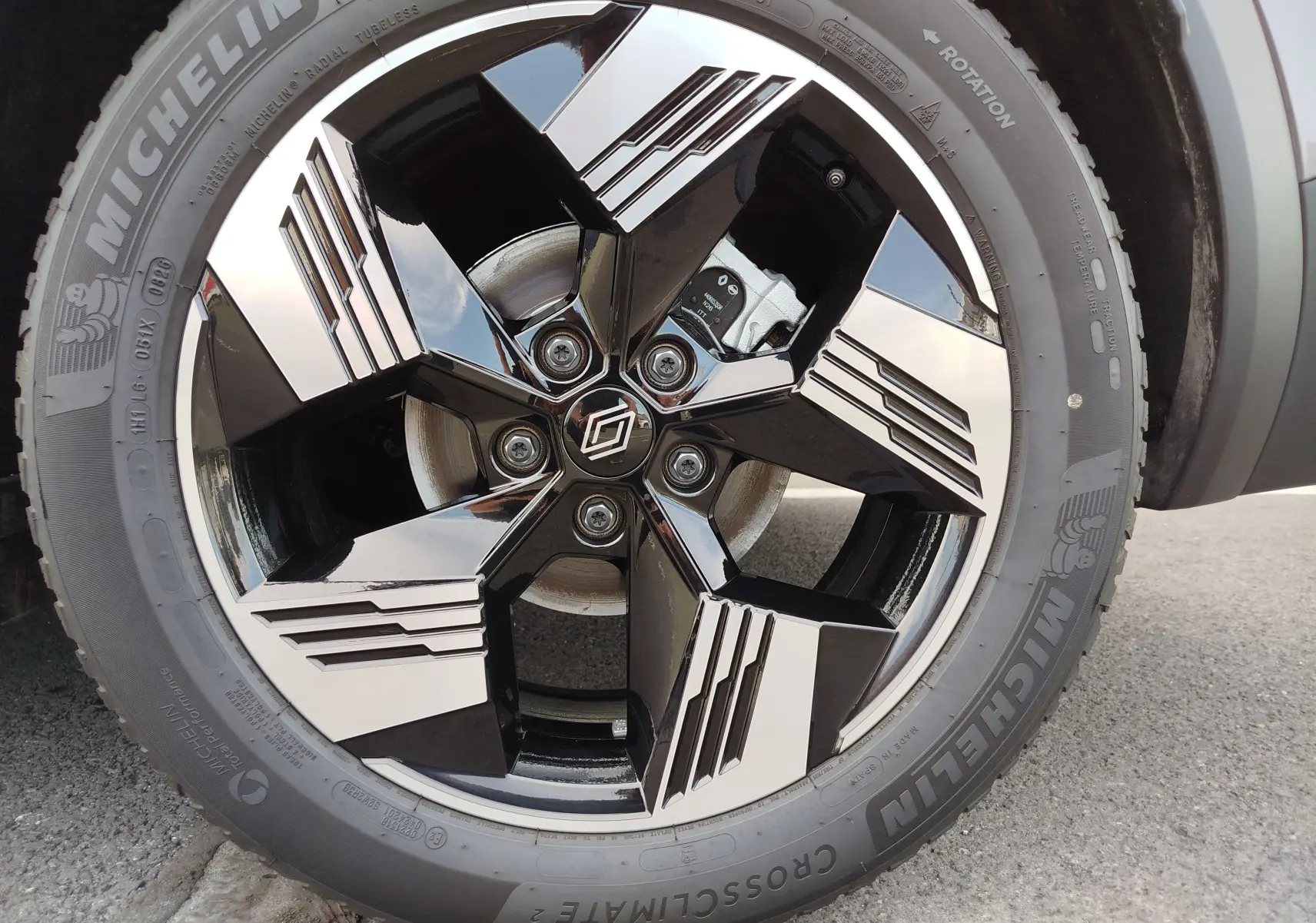 Gros plan sur la jante noire et argentée au design géométrique du Renault Symbioz gris Cassiopée Métal, pneu Michelin visible.