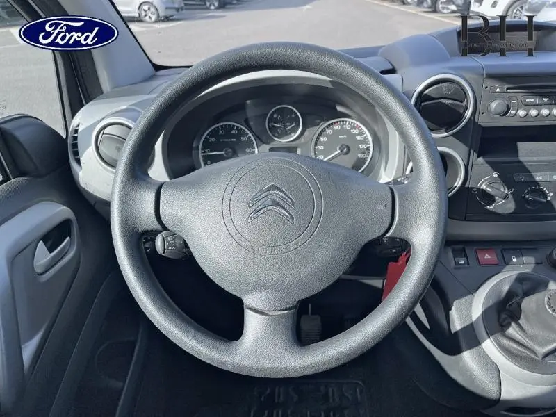 Vue intérieure centrée sur le volant noir du Citroën Berlingo blanc avec tableau de bord et commandes visibles