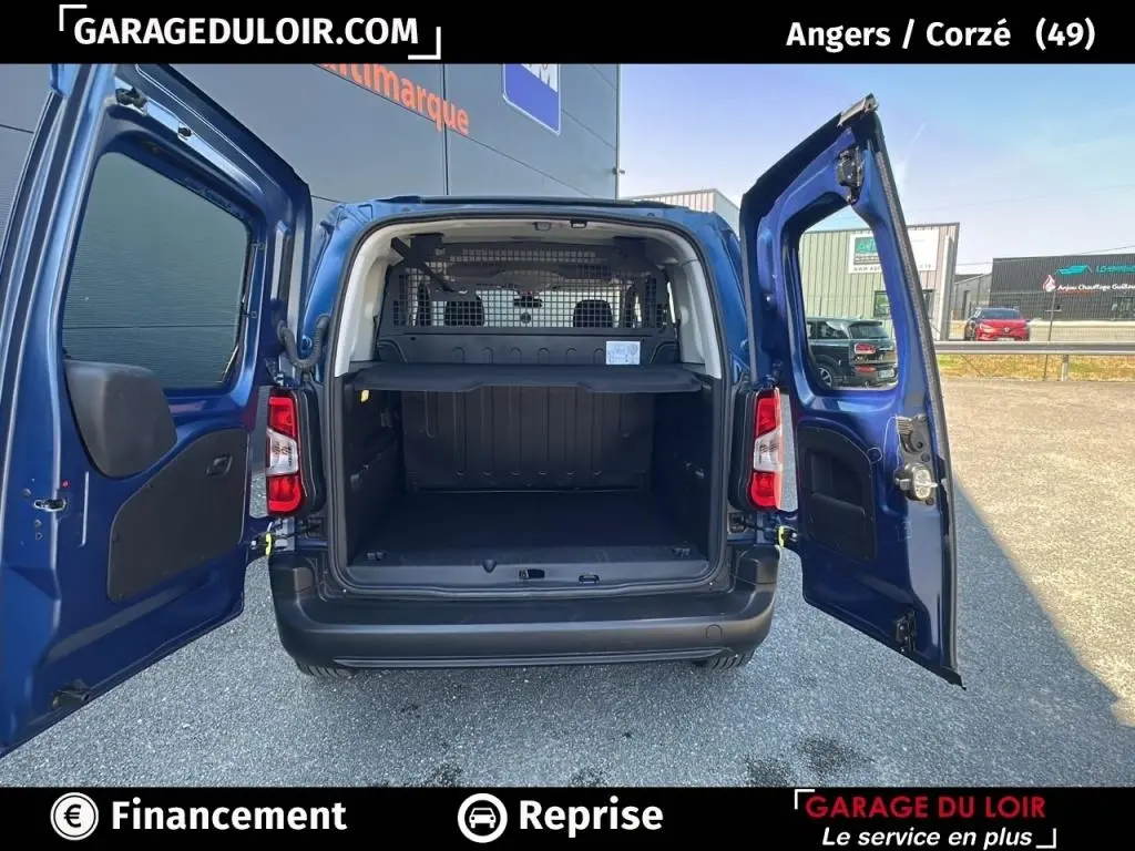 Vue arrière du Peugeot Rifter bleu 2024 avec portes ouvertes montrant le grand espace de chargement et la grille de séparation.