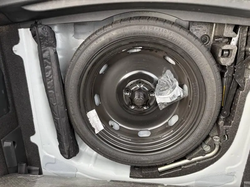 Roue de secours noire et outils de bord dans le coffre du CUPRA Formentor 2.0 TDI blanc Nevada métallisé, vue en plongée.