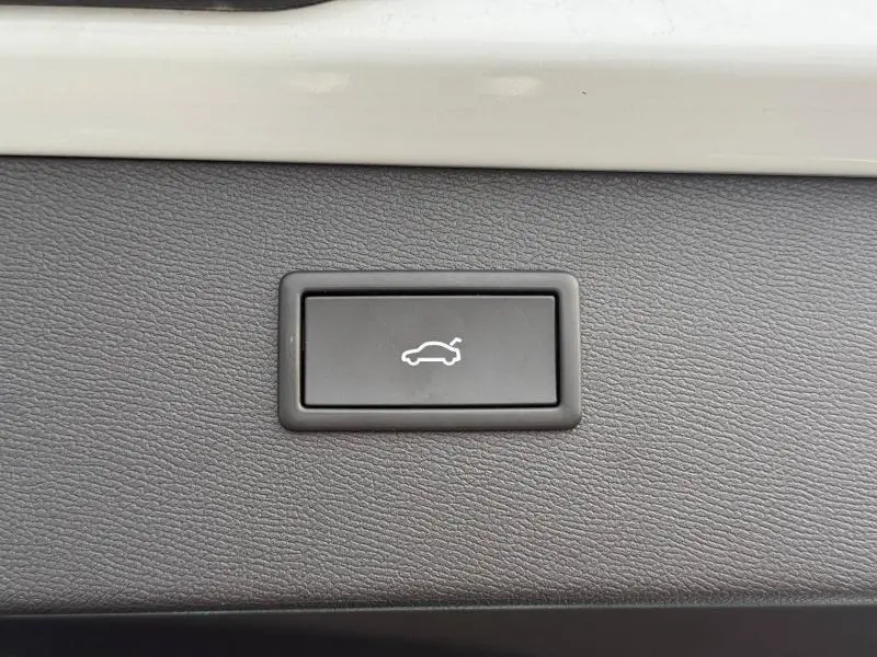 Bouton intérieur noir avec symbole d'ouverture de coffre, sur tableau de bord gris clair du CUPRA Formentor 2025 blanc Nevada.