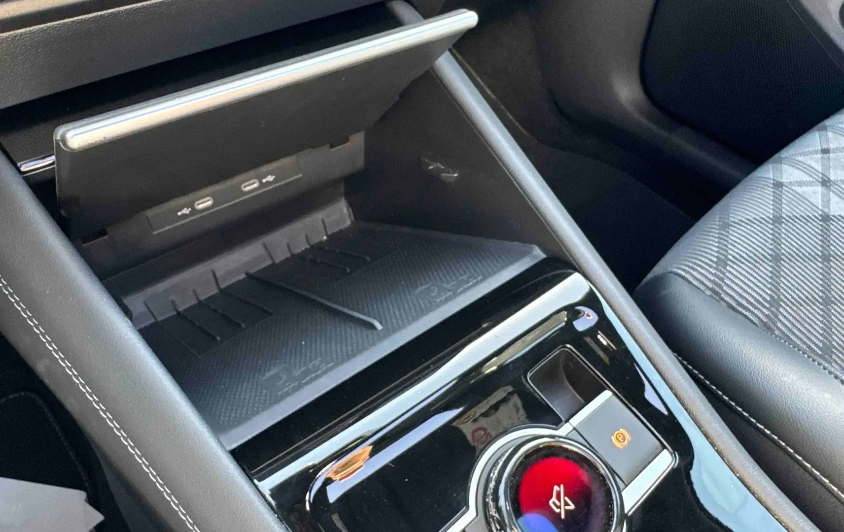 Gros plan sur la console centrale noire brillante du Volkswagen Tiguan 2025 avec chargeur sans fil et frein de stationnement électronique.