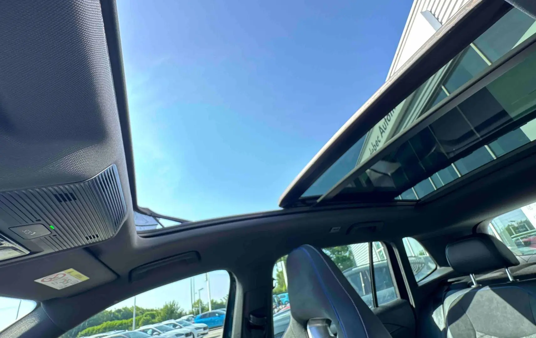 Vue intérieure du toit ouvrant panoramique et des sièges avant en cuir noir du Volkswagen Tiguan bleu 2025.