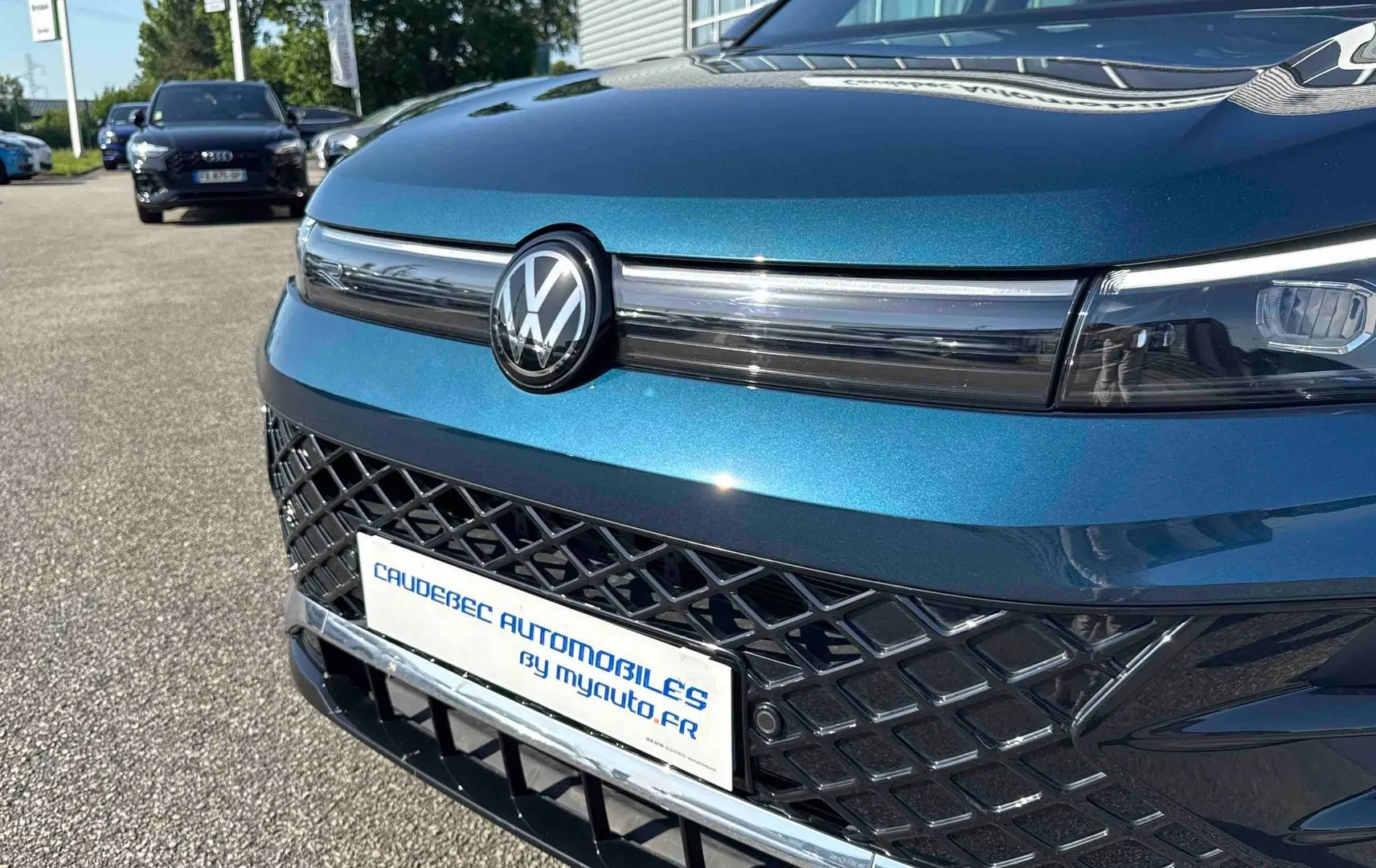 Gros plan sur l’avant bleu métallisé du Volkswagen Tiguan 2025 avec calandre ajourée et logo VW central.