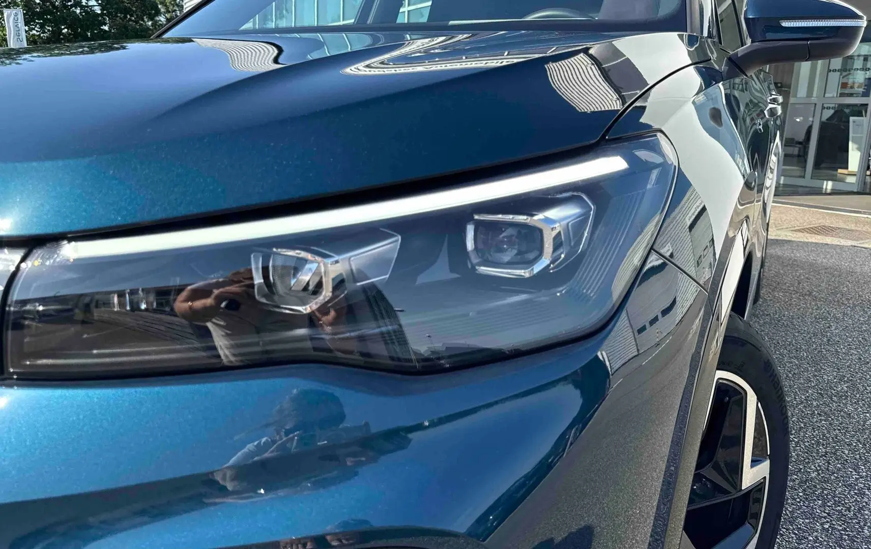 Gros plan sur le phare avant droit et la jante alliage 19 pouces d’un Volkswagen Tiguan bleu métallisé.