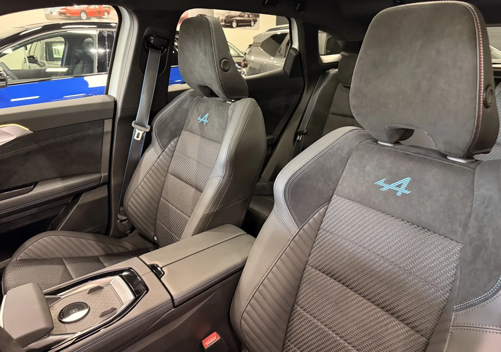 Vue intérieure sur les sièges avant en cuir noir avec surpiqûres bleues et logo Alpine brodé sur un Renault Austral 2026.