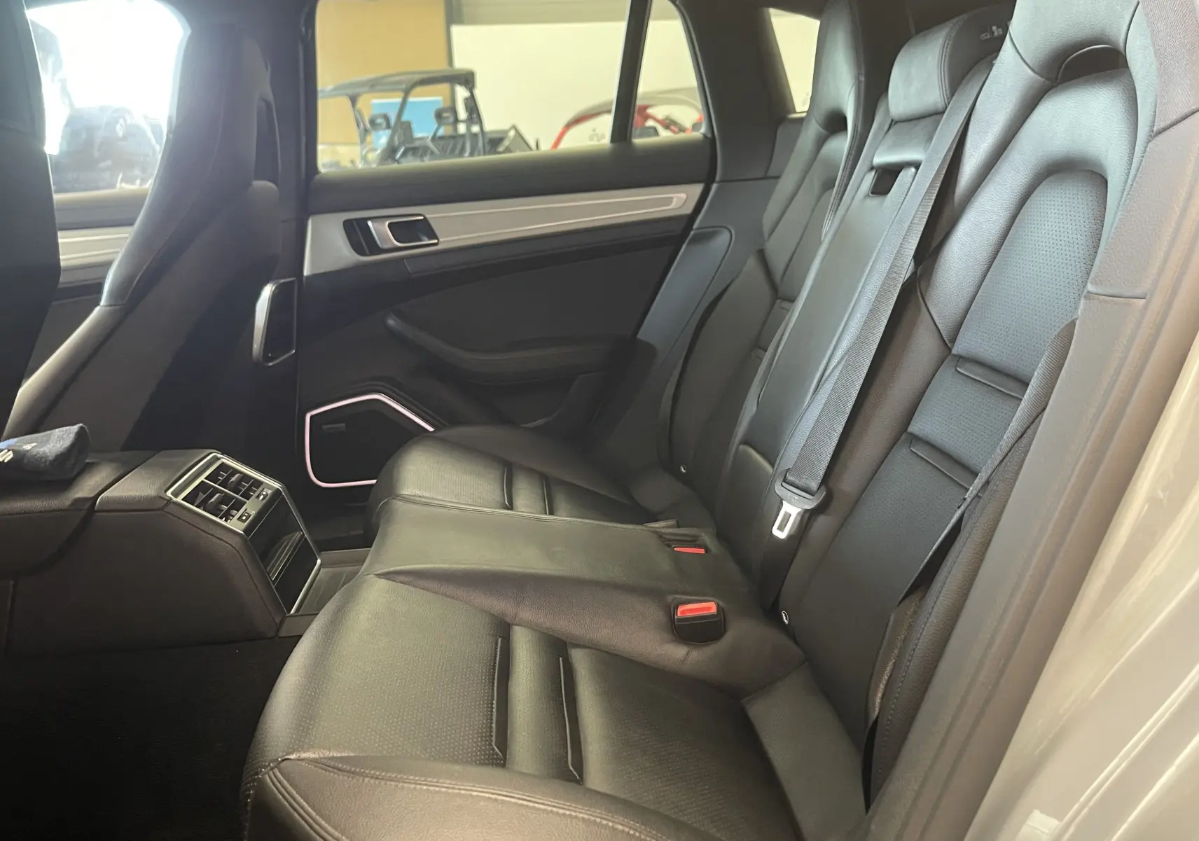 Vue intérieure des sièges arrière en cuir noir du Porsche Panamera Sport Turismo gris, mettant en valeur l'espace et les finitions soignées.