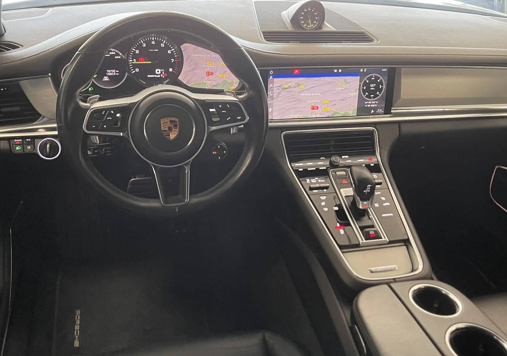 Vue intérieure du tableau de bord et volant noir de la Porsche Panamera Sport Turismo hybride avec écran de navigation allumé.