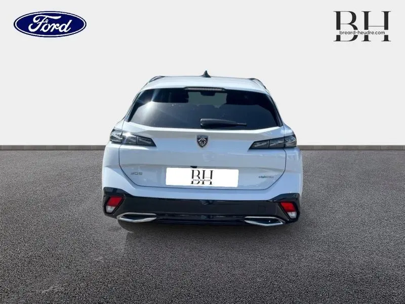 Vue arrière d'une Peugeot 308 SW PHEV 180ch GT blanche Okénite avec feux LED et double sortie d'échappement chromée.