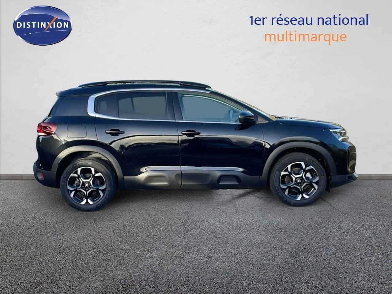 Profil côté gauche d'un Citroën C5 Aircross noir Perla Metal avec jantes alliage et barres de toit visibles.