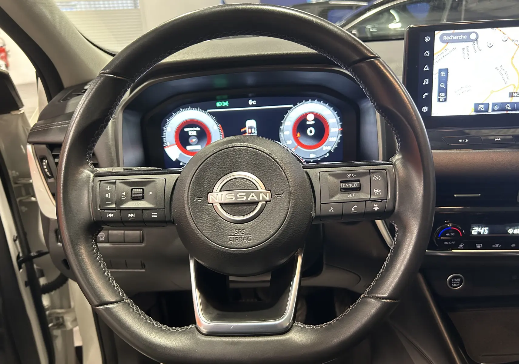 Vue centrée sur le volant cuir noir du Nissan Qashqai 2023 avec tableau de bord numérique et écran GPS visible.