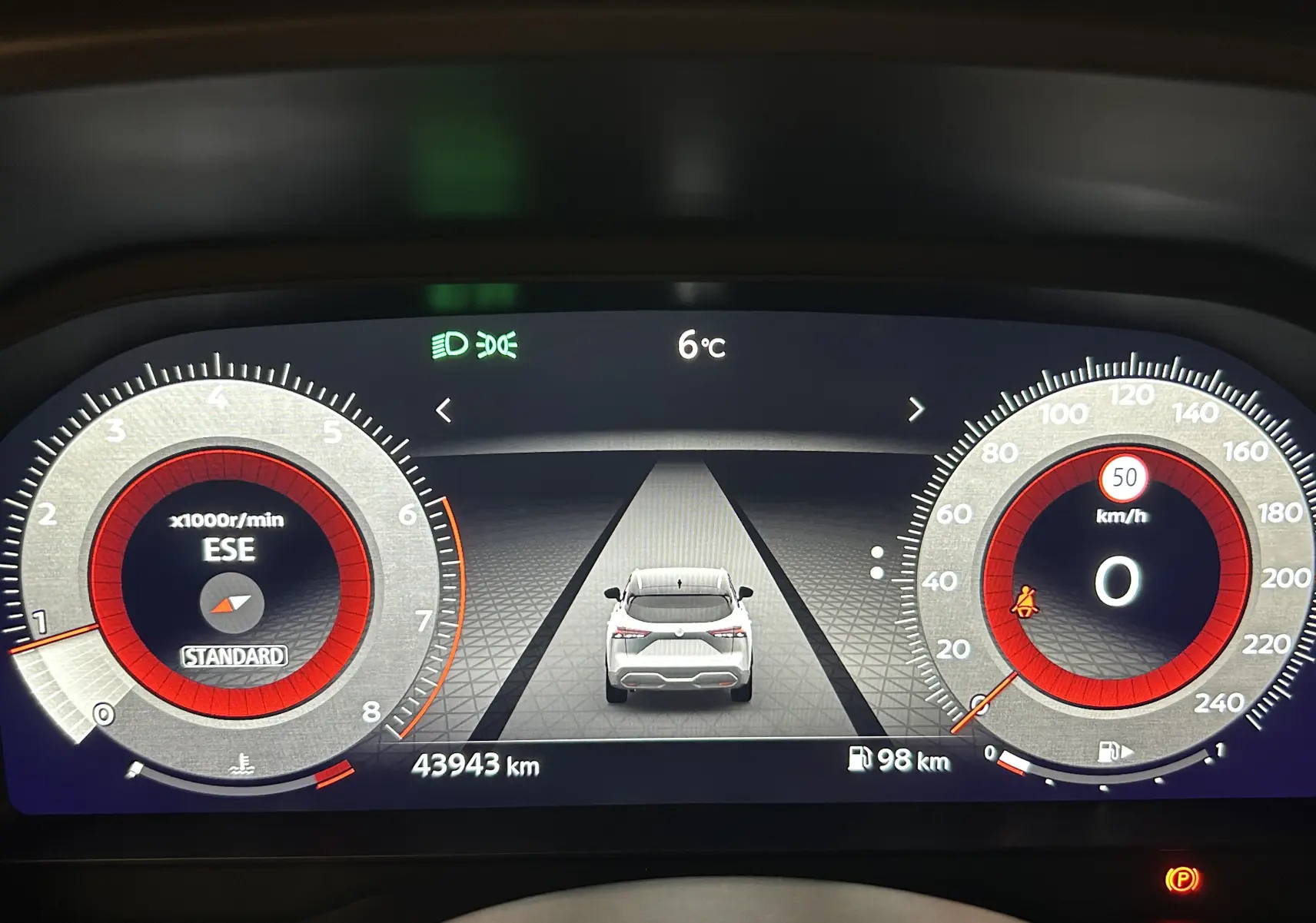 Tableau de bord numérique du Nissan Qashqai 1.3 Hybrid blanc, affichant la vitesse, régime moteur et température extérieure.