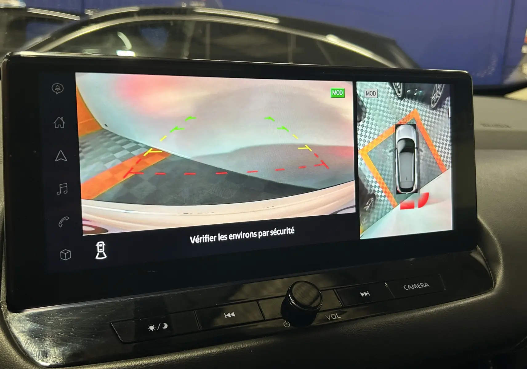 Écran multimédia du Nissan Qashqai blanc lunaire 2023 montrant la caméra 360° et l’aide au stationnement en marche arrière.