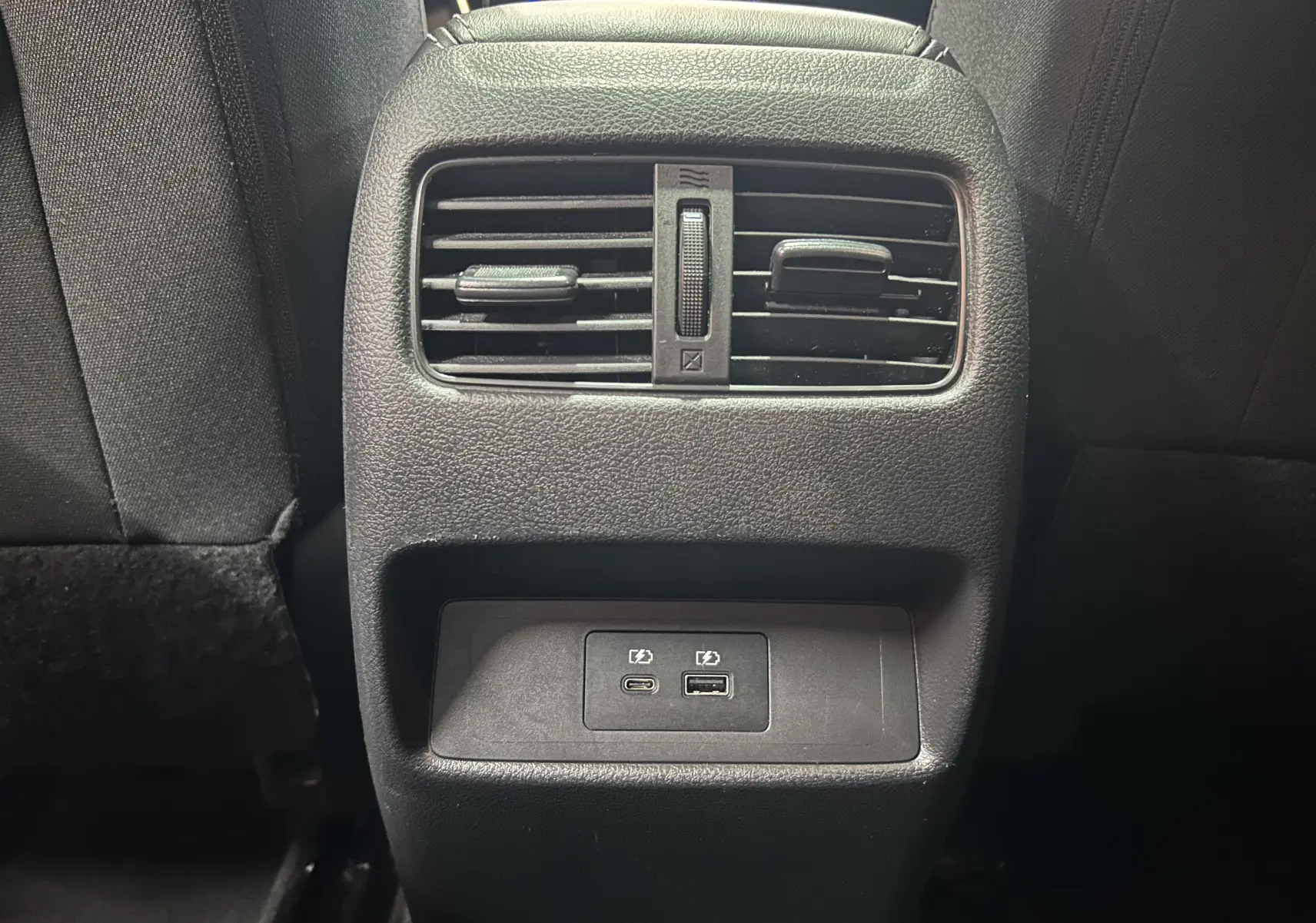 Détail de la console arrière noire du Nissan Qashqai 1.3 Hybrid 140 N-Connecta avec prises USB et aérateurs.