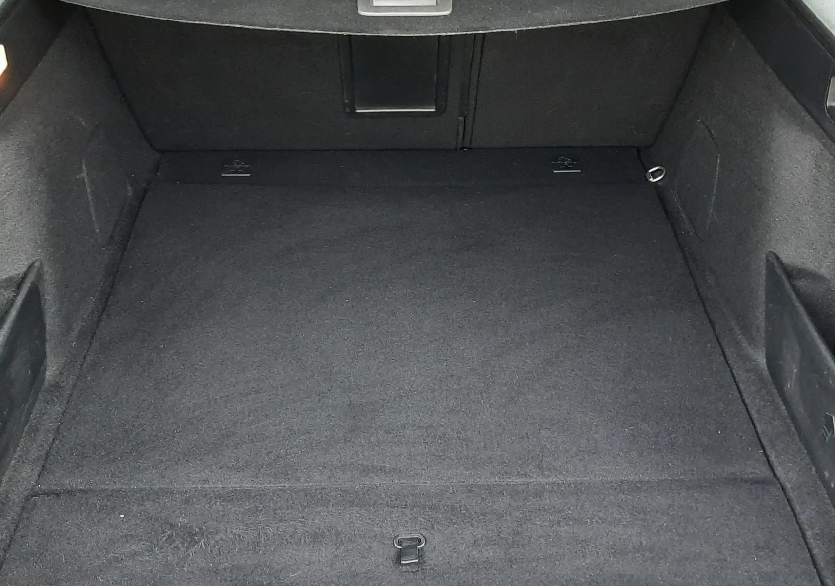 Vue plongeante sur le coffre spacieux et noir du Peugeot 308 SW 1.2 PureTech 2021, avec cache-bagages déployé.