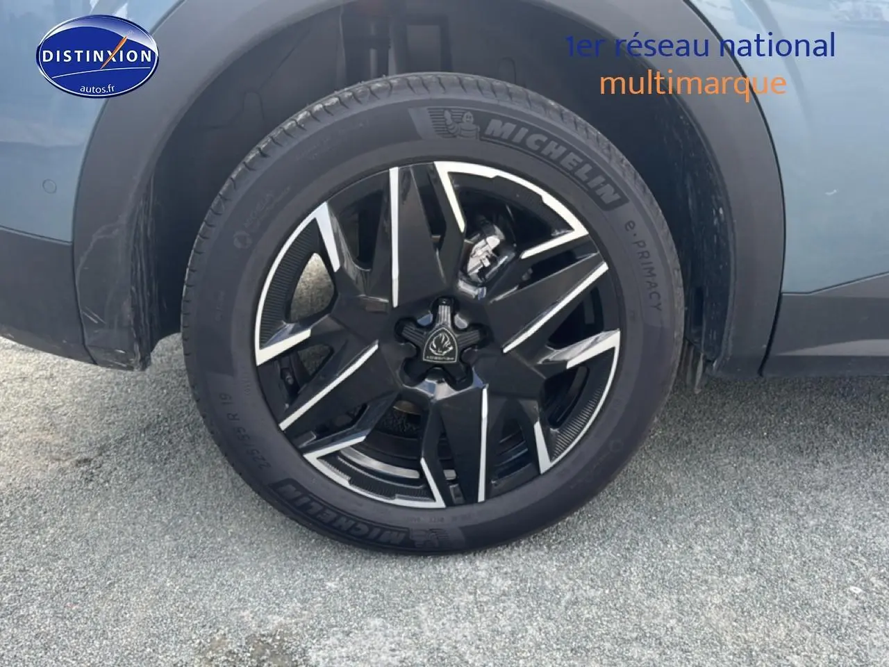 Gros plan sur la roue avant gauche avec jante alu noire et argentée du Peugeot 3008 bleu 2025 hybride.
