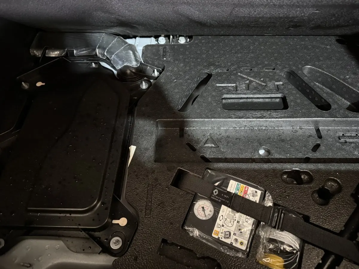 Détail du compartiment de rangement sous le coffre de la Renault Clio Business E-Tech hybride gris clair, avec kit de réparation.