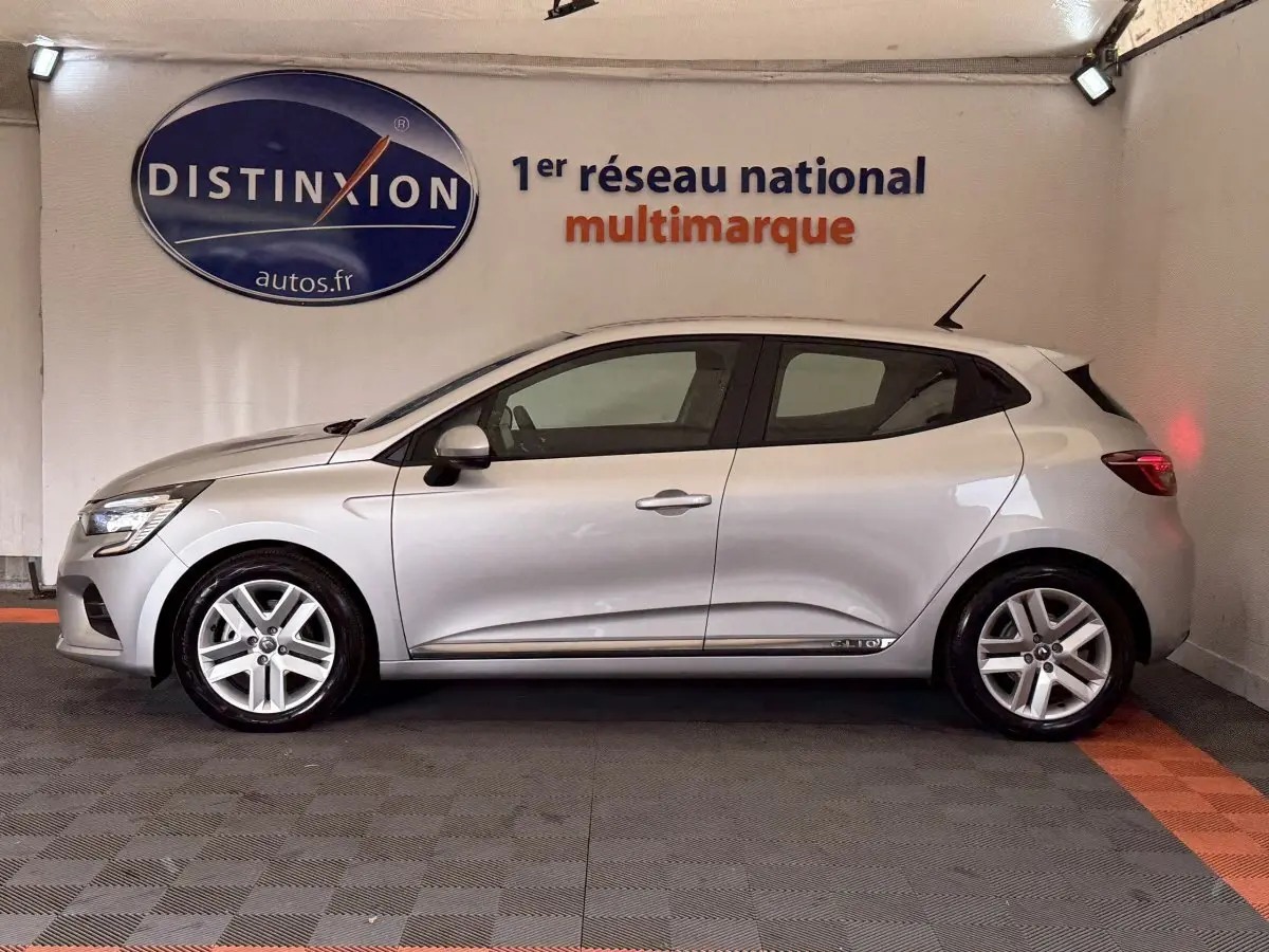 Profil droit d'une Renault Clio Business E-Tech hybride gris clair, avec jantes alliage et antenne de toit visible.