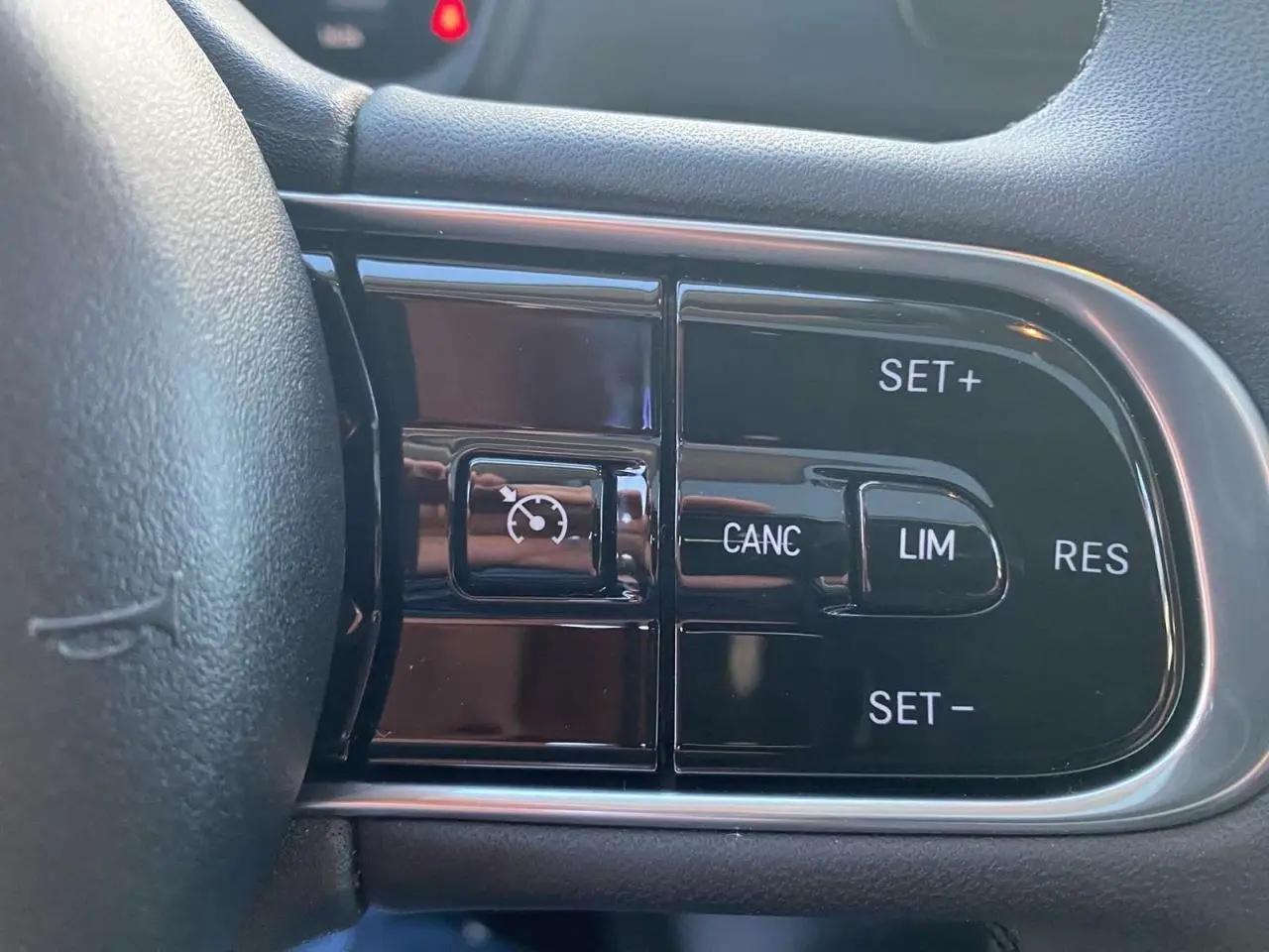 Gros plan sur les commandes du régulateur de vitesse sur le volant noir de la Fiat 500 électrique 2022.