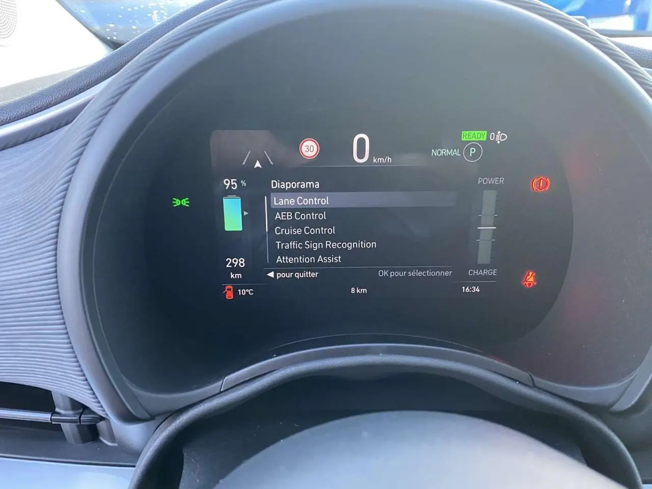 Tableau de bord numérique de la Fiat 500 électrique noire, affichant les aides à la conduite et l'autonomie restante.