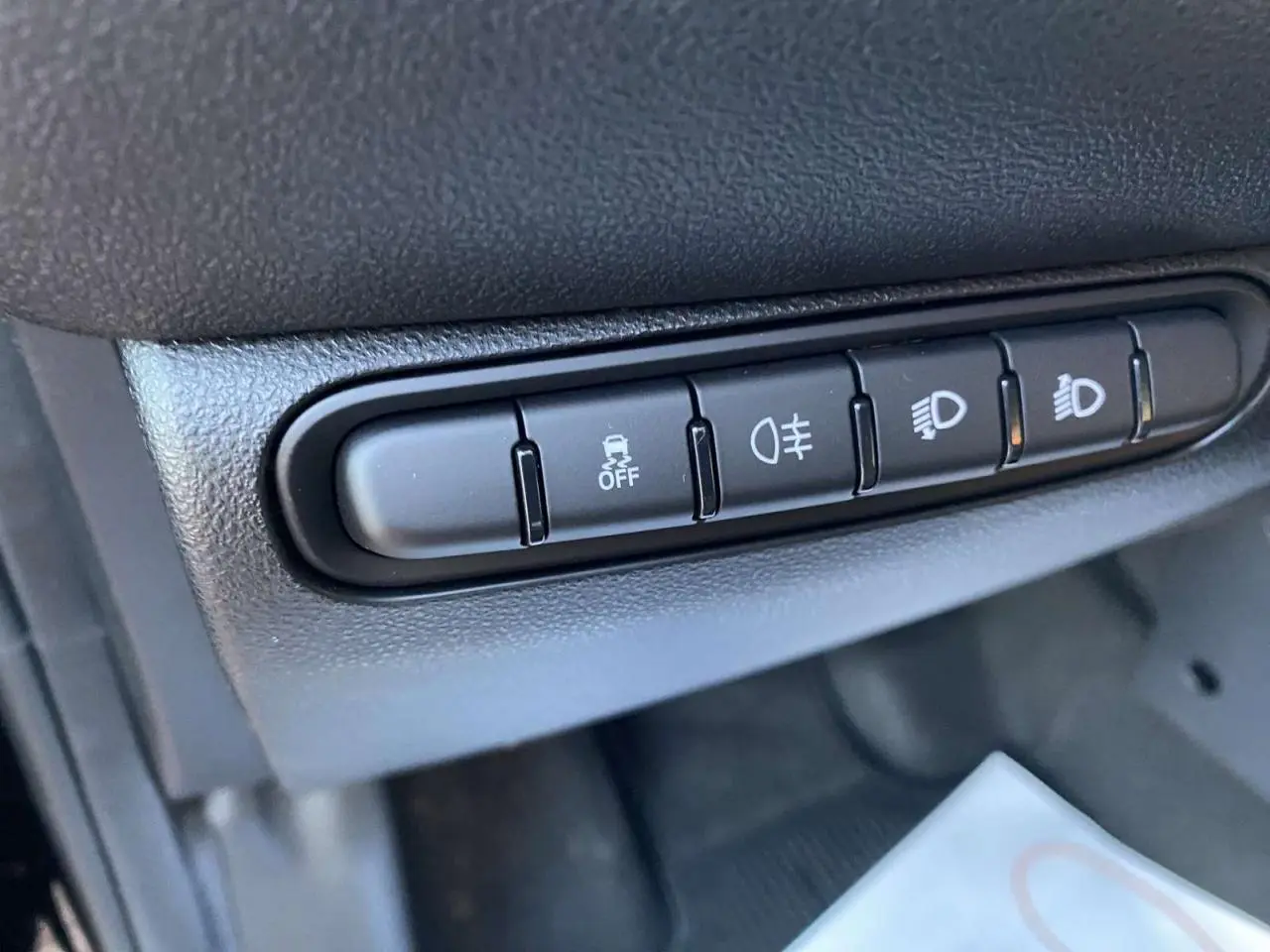 Gros plan sur les boutons de contrôle des feux et de l'ESP dans l'habitacle noir de la Fiat 500 électrique 2022.