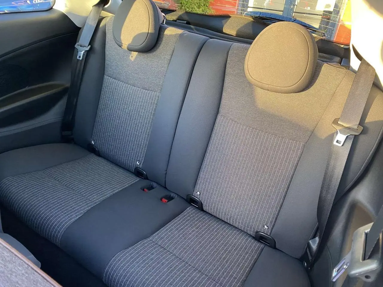 Vue intérieure arrière des sièges arrière en tissu gris foncé à rayures verticales de la Fiat 500 électrique noire 2022.