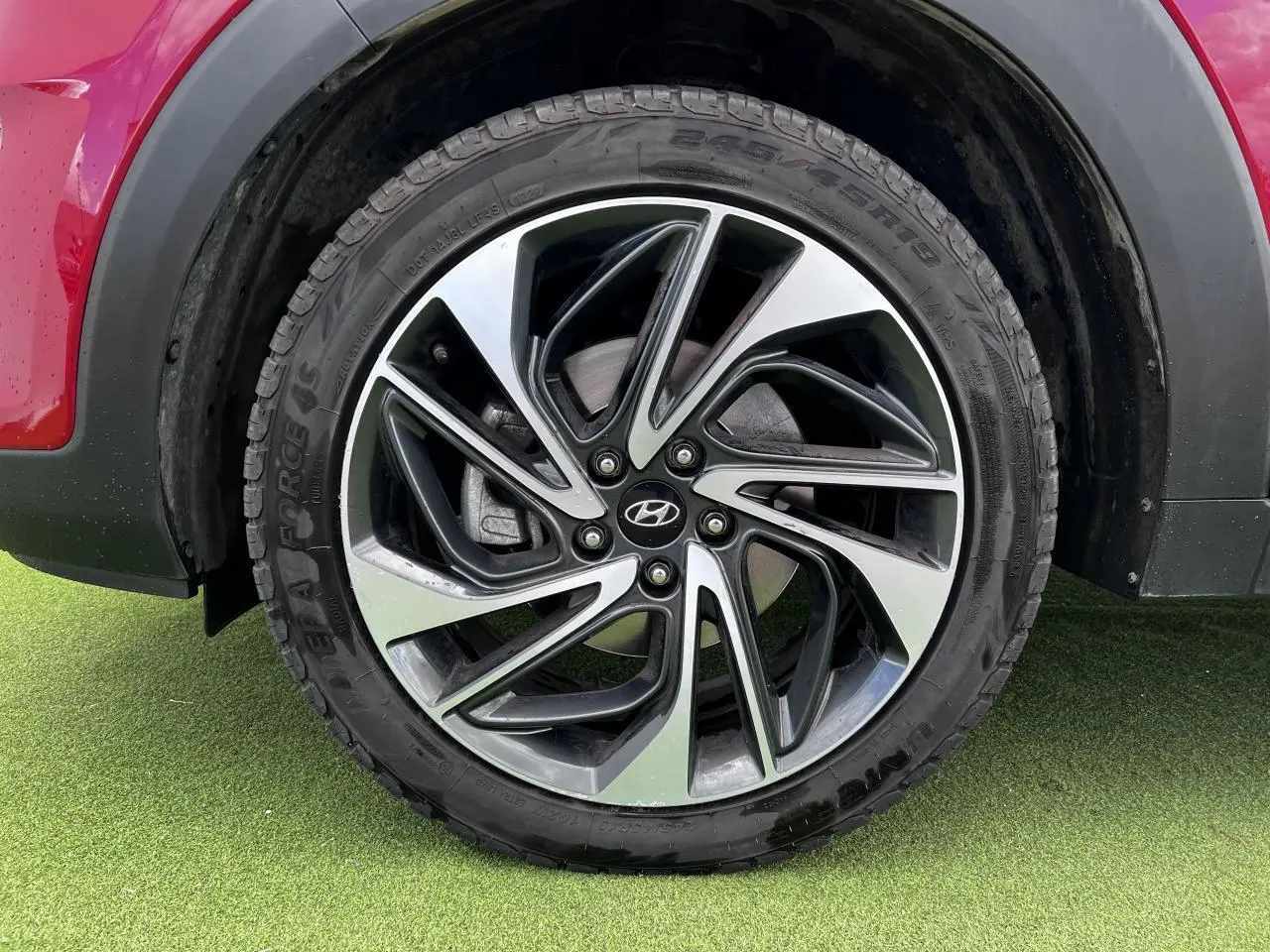 Gros plan sur la jante alliage 17'' bicolore du Hyundai Tucson III rouge métallisé, côté arrière droit.