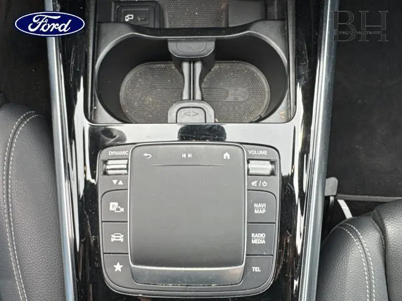 Vue plongeante sur la console centrale noire brillante avec pavé tactile et commandes multimédia d'un Mercedes GLA bleu denim.