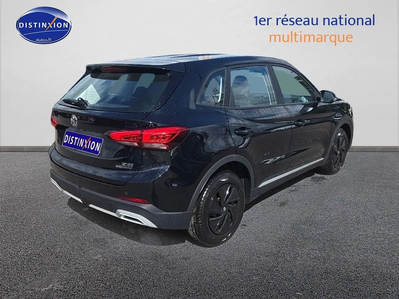 Vue 3/4 arrière droite du SUV noir MG ZS Hybrid 197 avec jantes noires et feux arrière LED allumés.