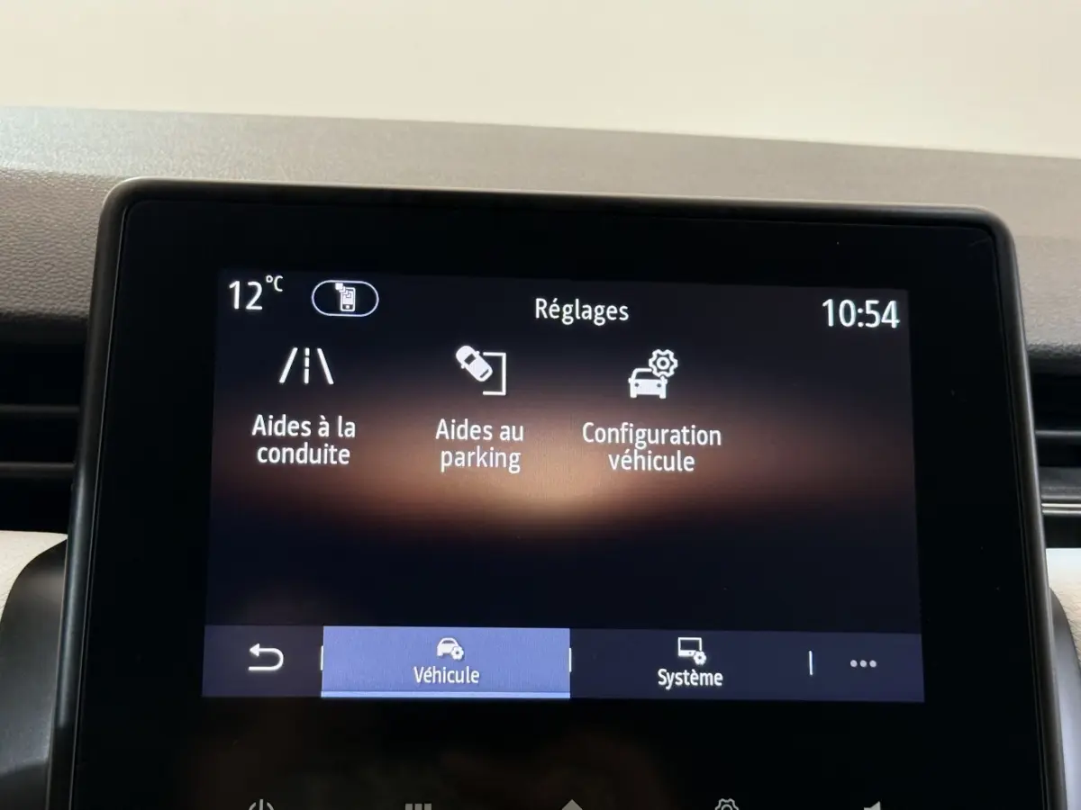 Écran tactile central de la Renault Clio blanc 2023 affichant les réglages d’aides à la conduite et au parking.