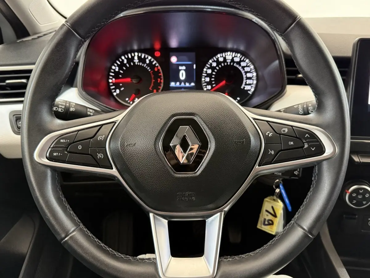 Vue centrée sur le volant cuir noir de la Renault Clio 2023 avec tableau de bord et commandes intégrées visibles.