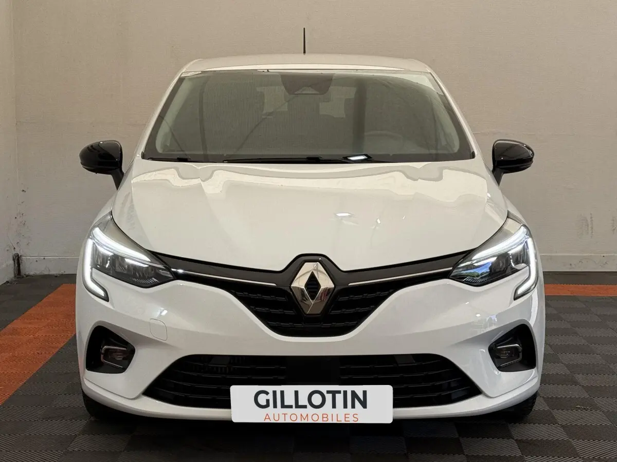 Vue avant d'une Renault Clio Evolution TCe 100 GPL blanche avec phares LED allumés et rétroviseurs noirs.