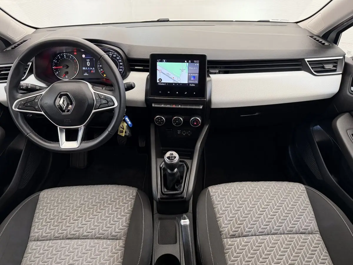 Vue intérieure avant de la Renault Clio Evolution TCe 100 GPL 2023, tableau de bord noir et beige avec écran tactile central.