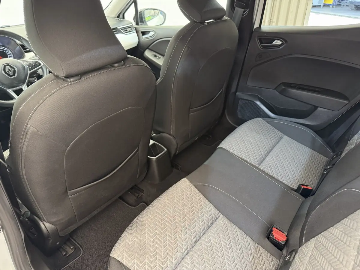 Vue intérieure arrière de la Renault Clio 2023, sièges tissu gris et noir avec motifs géométriques et portes noires.