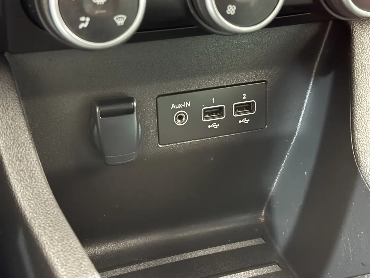 Vue rapprochée des ports USB et prise Aux-In noirs sur la console centrale de la Renault Clio blanche Evolution TCe 100 GPL.