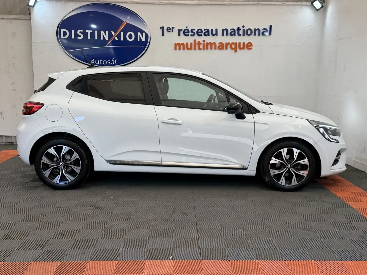 Profil droit d'une Renault Clio blanche 2023 Evolution TCe 100 GPL, avec jantes alliage et rétroviseurs noirs.